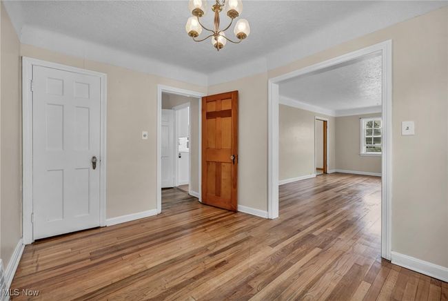 Unfurnished room featuring baseboards, a textured ceiling, hardwood / wood-style flooring, and an inviting chandelier | Image 30