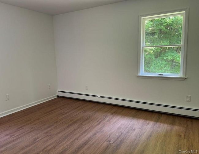 Spare room featuring baseboard heating and wood finished floors | Image 16