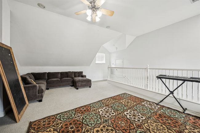 Living area featuring carpet, vaulted ceiling, a ceiling fan, and an upstairs landing | Image 28