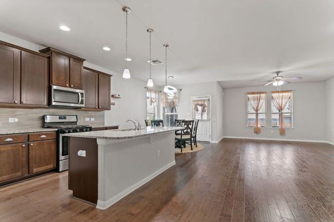 Kitchen with decorative backsplash, visible vents, stainless steel appliances, an island with sink, and a sink | Image 11