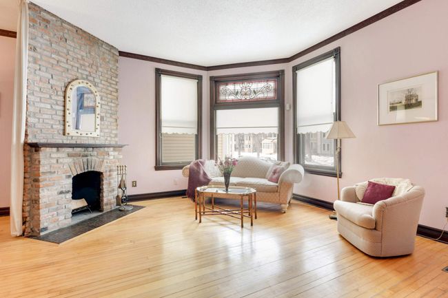 The generously sized living space has bow windows that flood the room with light. Note the custom stained glass transom window, a companion to the window over the entry door. | Image 7
