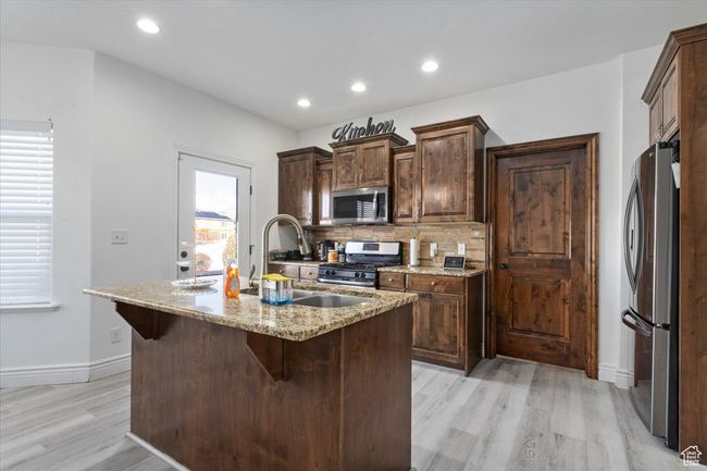 Kitchen with stainless steel appliances, a wealth of natural light, an island with sink, and light hardwood / wood-style floors | Image 8