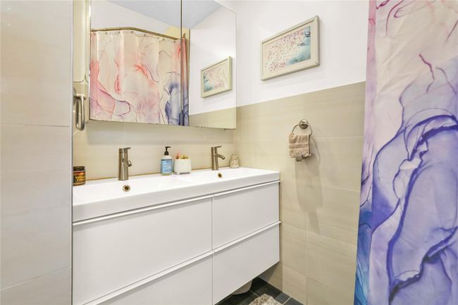 Full bath with double vanity, tile walls, and curtained shower | Image 9