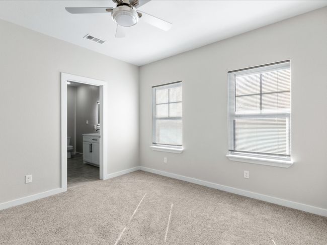 Unfurnished bedroom featuring visible vents, ceiling fan, baseboards, carpet, and ensuite bathroom | Image 18