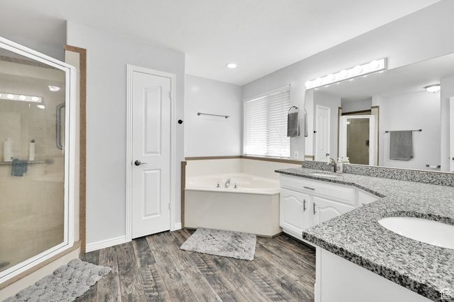 Bathroom featuring vanity, a bath, a stall shower, and wood finished floors | Image 18