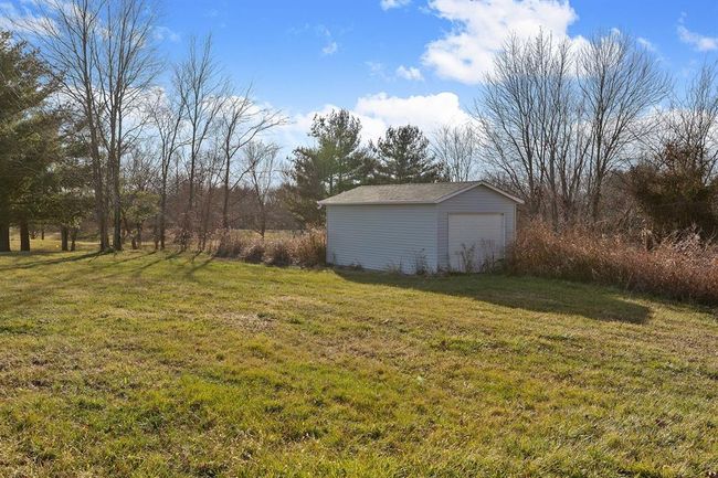 View of green lawn featuring an outbuilding and a detached garage | Image 25