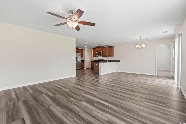 Unfurnished living room with a chandelier, a ceiling fan, and dark wood-style floors | Image 12