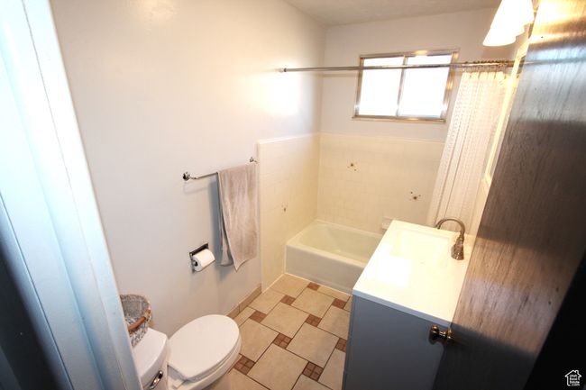 Bathroom with a bathtub, vanity, and curtained shower | Image 15