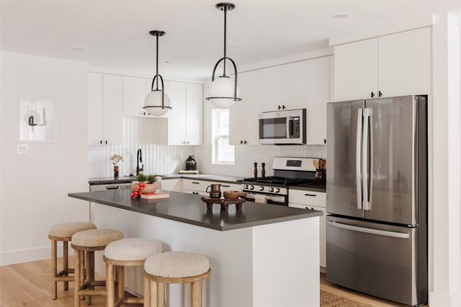 Kitchen with appliances with stainless steel finishes, dark countertops, a kitchen breakfast bar, and backsplash | Image 11