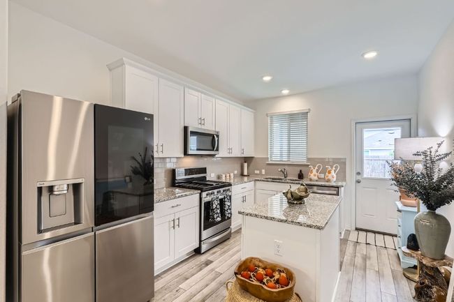 Kitchen featuring appliances with stainless steel finishes, a sink, white cabinets, decorative backsplash, and recessed lighting | Image 8