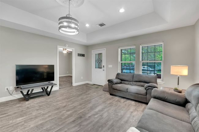Living area with visible vents, recessed lighting, wood finished floors, a raised ceiling, and baseboards | Image 13
