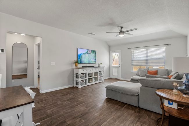 Living area featuring a ceiling fan, dark wood finished floors, a textured ceiling, and lofted ceiling | Image 9
