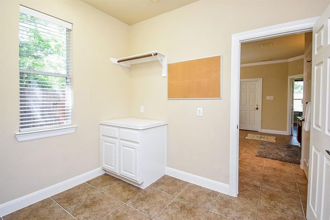 Spacious and well-planned, the laundry room includes countertop workspace, overhead shelving, and room to maneuver—making everyday chores feel a little less routine. | Image 8