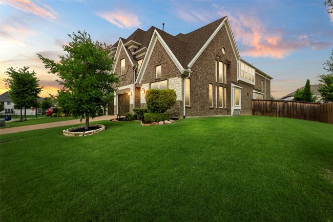 View of front facade with a shingled roof, brick siding, concrete driveway, an attached garage, and stone siding | Image 33