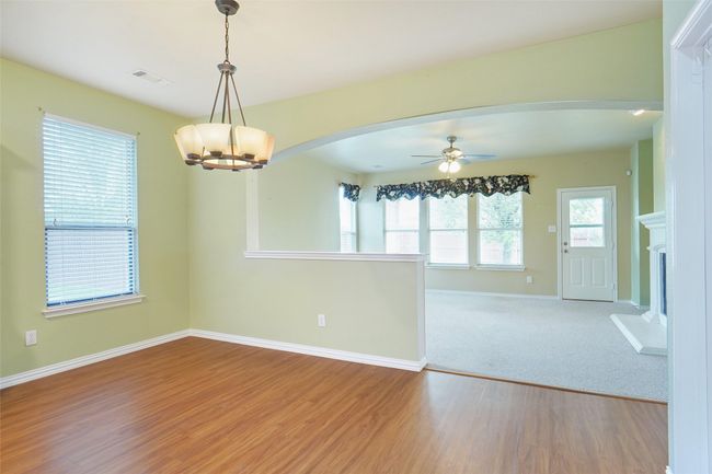 Unfurnished room with baseboards, wood finished floors, arched walkways, and ceiling fan with notable chandelier | Image 10
