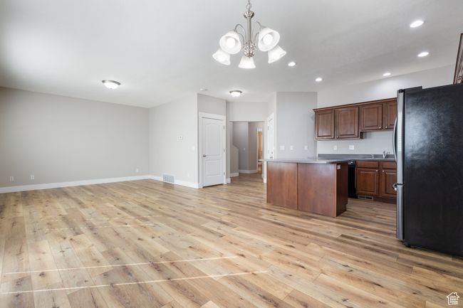 Kitchen with freestanding refrigerator, light wood-style flooring, a center island, recessed lighting, and open floor plan | Image 9