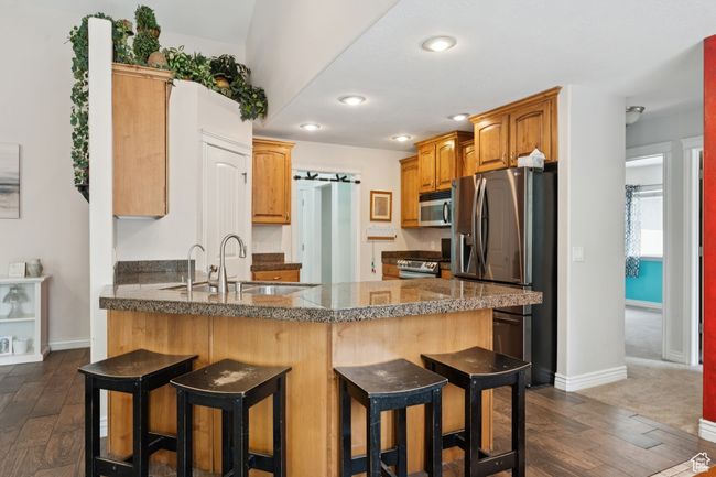 Kitchen with stainless steel appliances, a peninsula, a sink, tile counters, and a breakfast bar area | Image 9