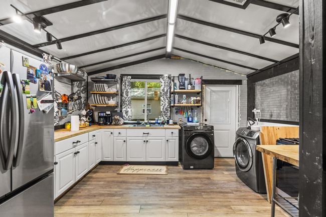 Kitchen with freestanding refrigerator, open shelves, light wood-style flooring, and white cabinetry | Image 9