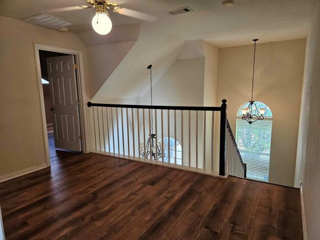 Unfurnished room with a ceiling fan, a chandelier, wood finished floors, and lofted ceiling | Image 6
