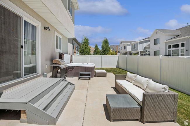 Fenced backyard with a hot tub, a patio, a residential view, an outdoor hangout area, and area for grilling | Image 32