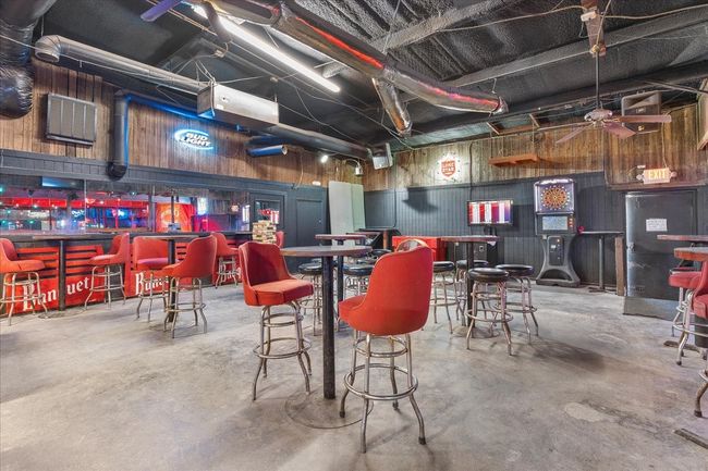 Misc room featuring unfinished concrete flooring, a bar, and wood walls | Image 12