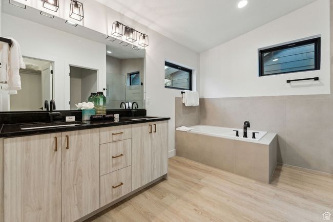 Bathroom featuring a relaxing tiled tub, hardwood / wood-style floors, and vanity | Image 20
