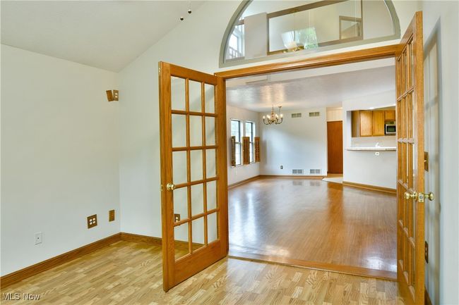 Unfurnished room with light wood-style flooring, a chandelier, lofted ceiling, and french doors | Image 16