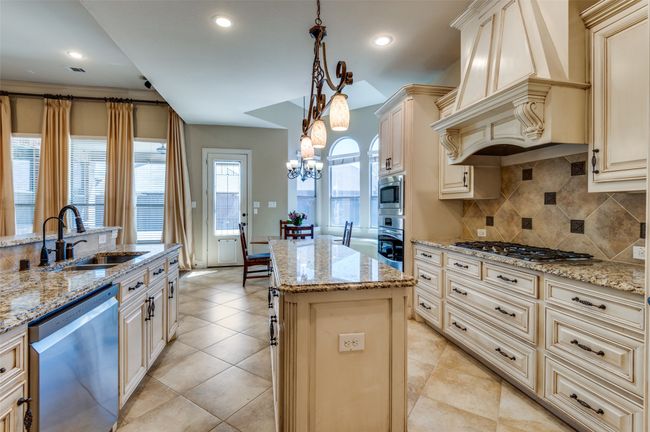 Kitchen with premium range hood, cream cabinets, stainless steel appliances, and a sink | Image 18