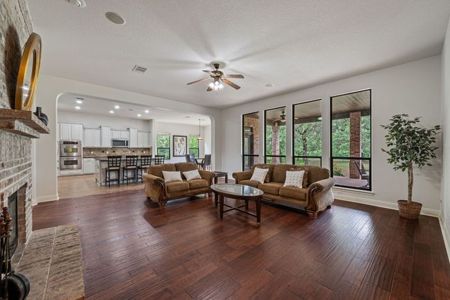 Living room featuring arched walkways, dark wood-style flooring, a fireplace, visible vents, and a ceiling fan | Image 8