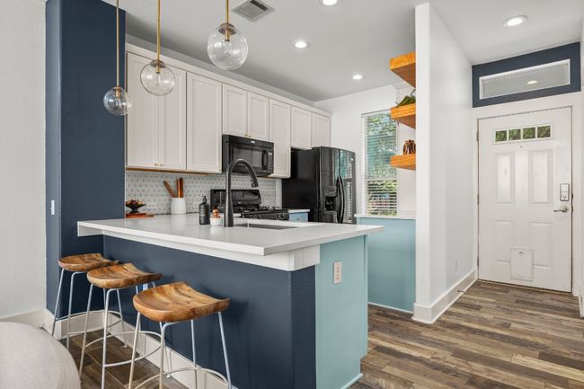 Kitchen with black appliances, open shelves, a peninsula, dark wood finished floors, and decorative backsplash | Image 4