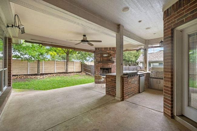 Fenced backyard featuring an outdoor brick fireplace, a patio, and ceiling fan | Image 28
