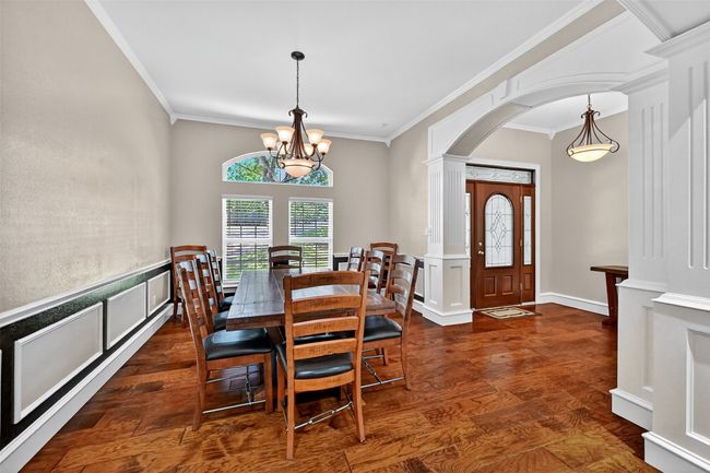 Dining room featuring arched walkways, crown molding, dark wood-style flooring, and a chandelier | Image 8
