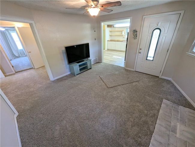 Carpeted entrance foyer with a ceiling fan, a textured ceiling, and baseboards | Image 11