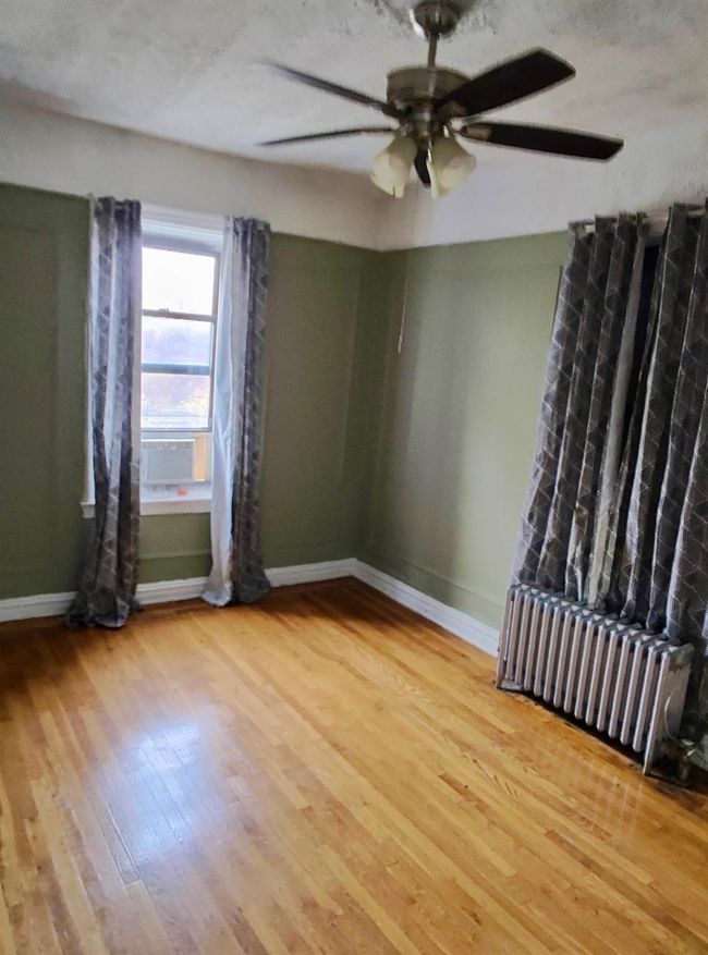 Spare room with ceiling fan, radiator heating unit, light wood-type flooring, and baseboards | Image 16