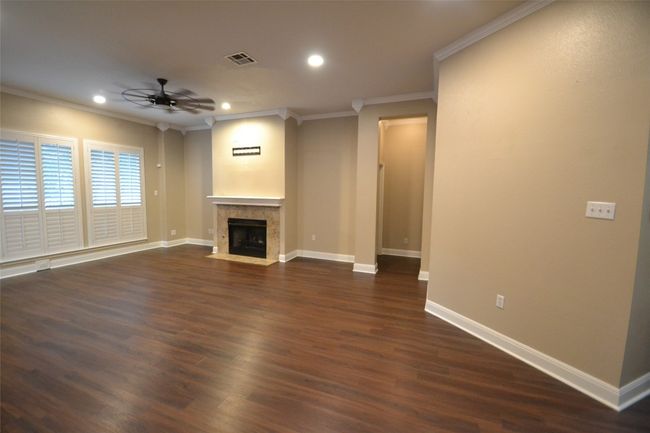 Unfurnished living room with a ceiling fan, crown molding, dark wood-style floors, recessed lighting, and a fireplace with flush hearth | Image 8