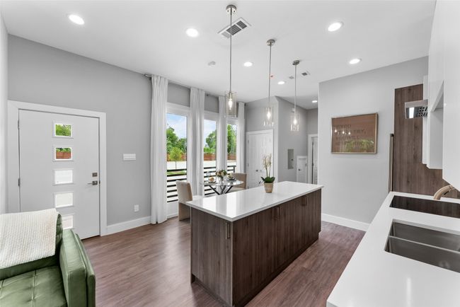 Kitchen featuring dark brown cabinetry, visible vents, a center island, light countertops, and a sink | Image 8