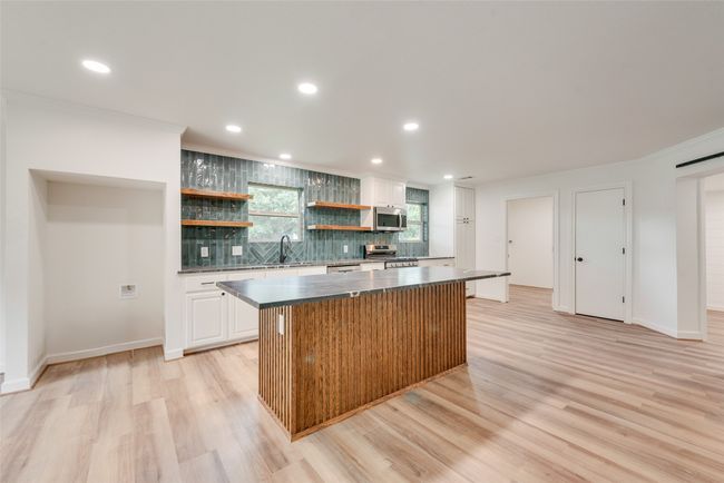 Kitchen featuring stainless steel appliances, open shelves, backsplash, a kitchen island | Image 12