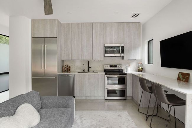 Kitchen with stainless steel appliances, modern cabinets, a sink, finished concrete floors, and light countertops | Image 33