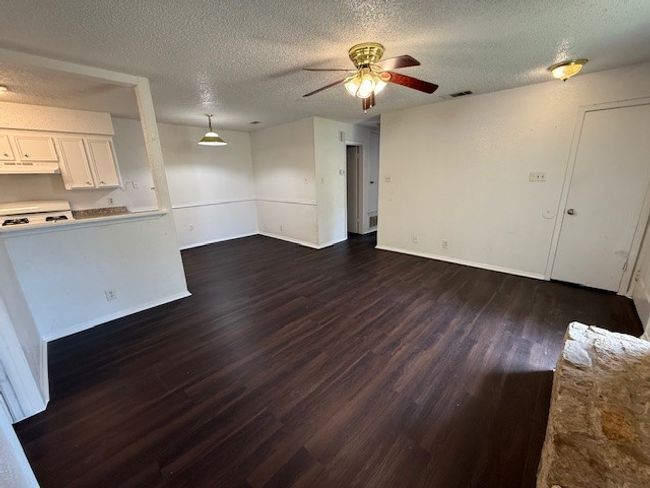 Unfurnished living room featuring dark wood-style floors, a textured ceiling, and a ceiling fan | Image 5