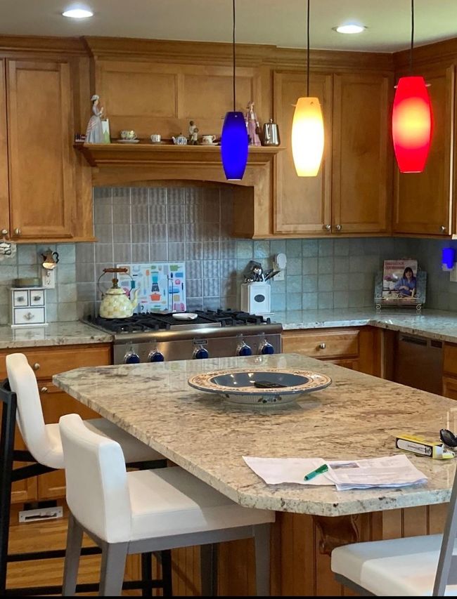 Kitchen featuring brown cabinets, wood finished floors, light stone countertops, and pendant lighting | Image 13