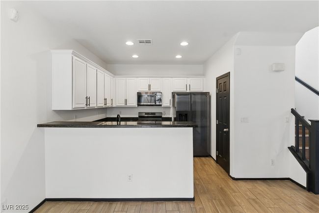 Kitchen featuring white cabinetry, appliance, and peninsula | Image 10
