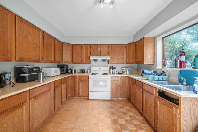 Kitchen featuring white appliances, light countertops, under cabinet range hood, brown cabinets, and a sink | Image 23