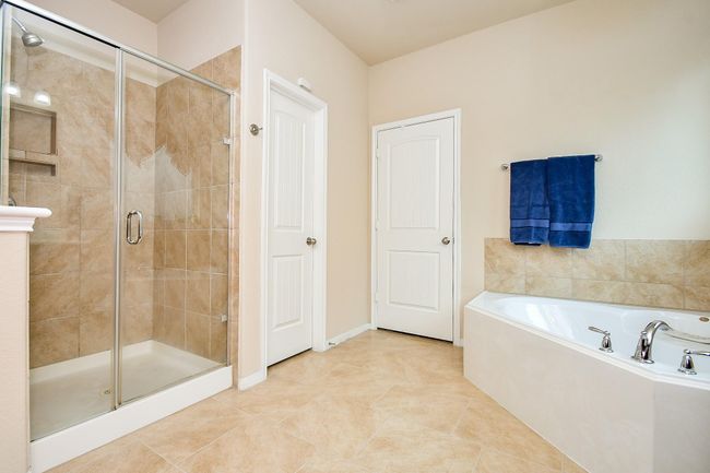 Spacious walk-in shower with glass doors and elegant tile work. | Image 19