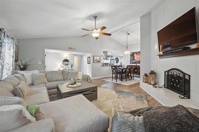 Living room featuring wood finished floors, a ceiling fan, and lofted ceiling | Image 8