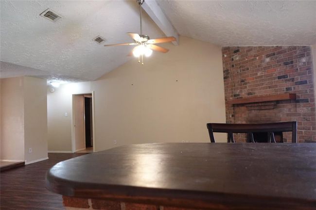 Spacious living area featuring a cozy brick fireplace and vaulted ceiling, perfect for relaxation and entertaining. | Image 18