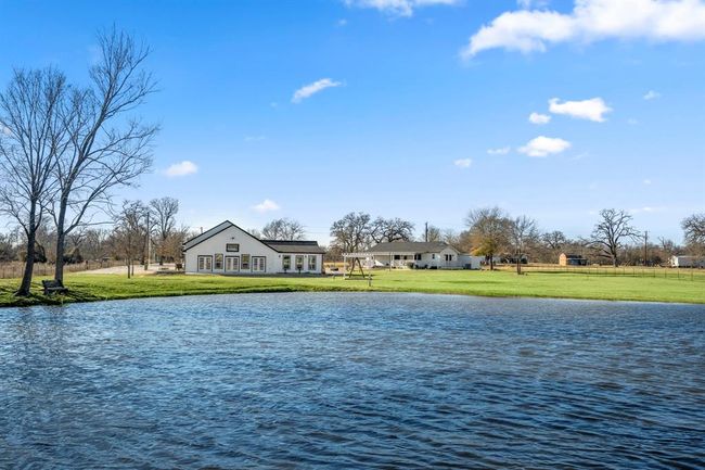 View of the main home and other building from across the pond—showcasing the property’s open space and tranquil setting. | Image 37