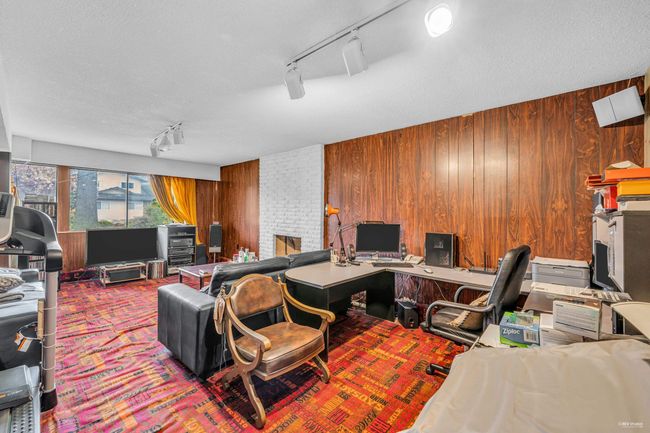 Carpeted office with track lighting, wood walls, and a brick fireplace | Image 5