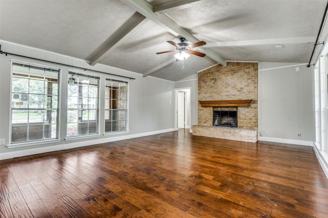 Unfurnished living room with hardwood / wood-style flooring, ceiling fan, and a fireplace | Image 5