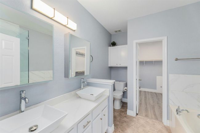 Full bathroom with a garden tub, double vanity, a walk in closet, tile patterned flooring, and a shower | Image 16
