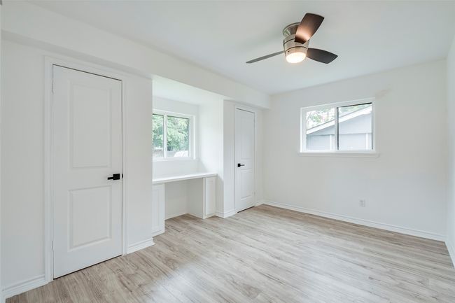 Unfurnished bedroom with light wood-type flooring, multiple windows, an office area, and ceiling fan | Image 18